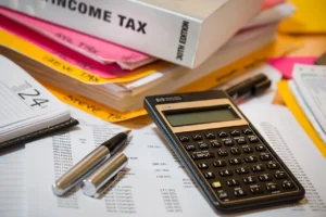 desk full of income tax documents, calculator, binder, and pens