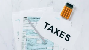 What happens if I file my taxes late? - tax documents sitting on s table with a calculator