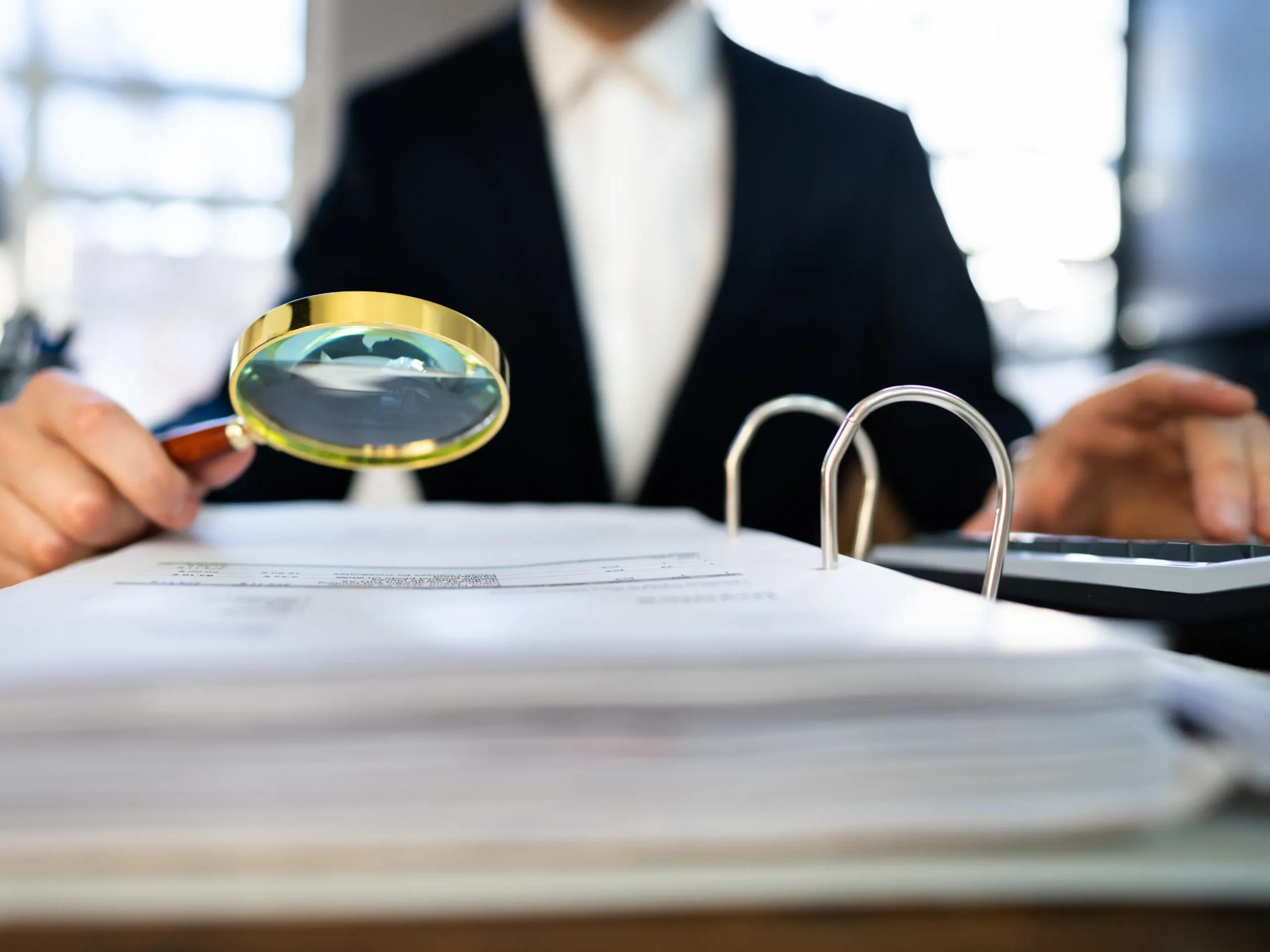 man looking at tax forms using a magnifying lens