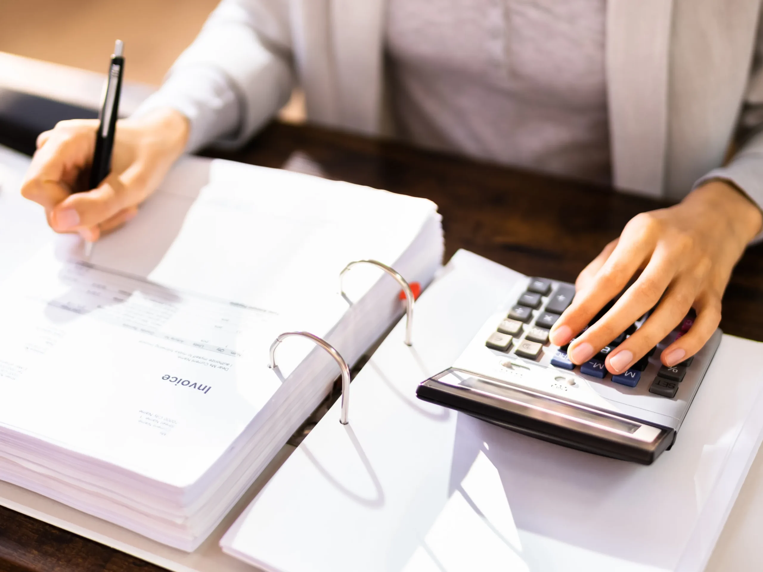 man calculating taxes using a calculator and holding a pen