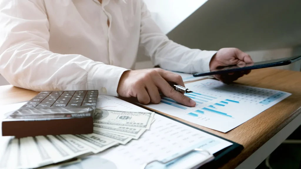 man sitting at desk sorting through tax documents with paper bills and calculator