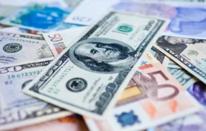 IRS penalties for unreported foreign accounts and income - U.S. $100 bill sitting on top of stack of other foreign money (fbar filing)