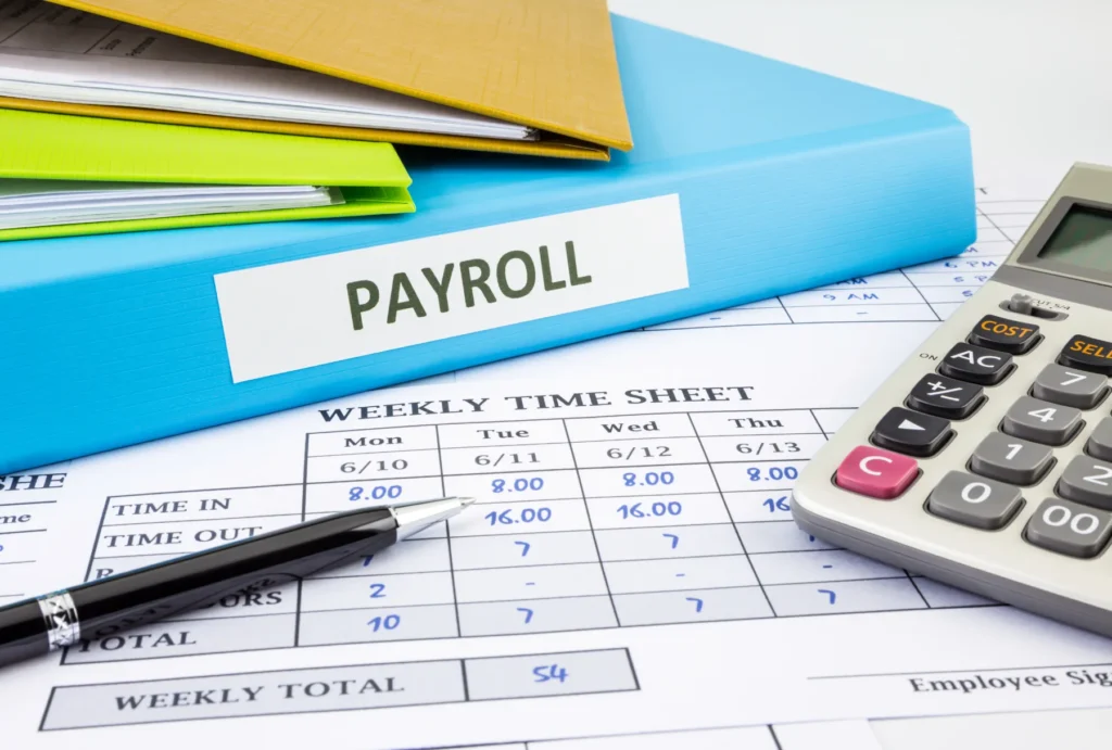 payroll taxes represented by time sheets, a stack of papers, and a calculator