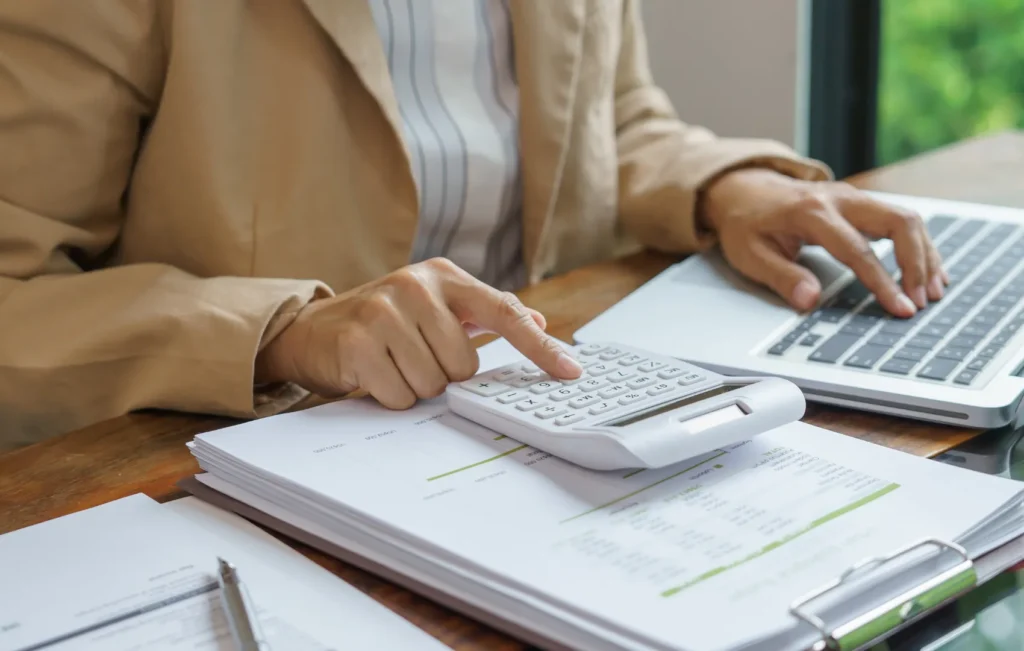 woman sitting at desk with a laptop, tax documents, and calculator to understand tax brackets for 2026